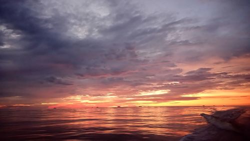 Scenic view of sea against cloudy sky at sunset