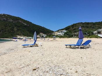 People on beach against clear blue sky