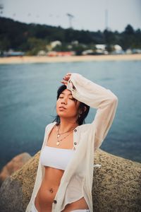 Beautiful young woman standing by lake