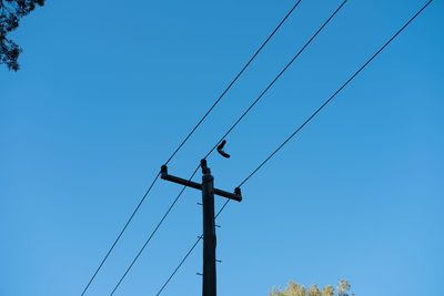 Low angle view of crane against clear blue sky