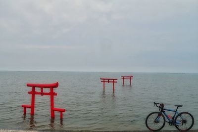 Bicycle by sea against sky