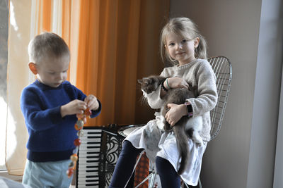 Two kids playing with a cat at home