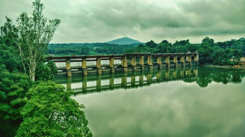 Bridge over river against cloudy sky