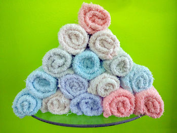 Close-up of colorful towels rolled up on table against green background