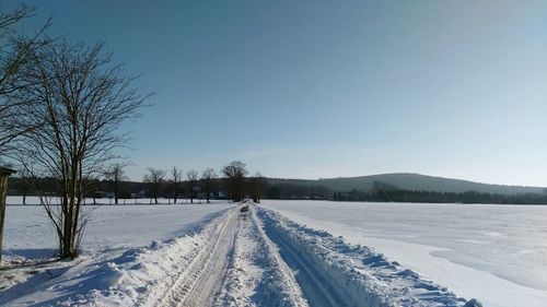 Snow covered field against clear sky