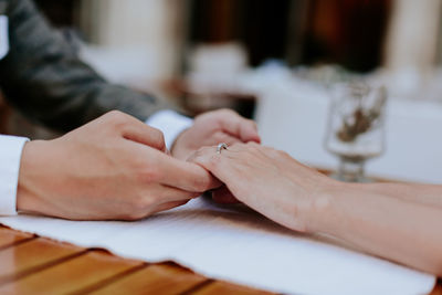 Cropped image of couple holding hands at table