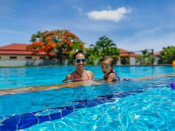 Pretty thai mother with her little baby in the swimming pool