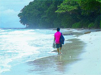 Rear view of man walking on beach