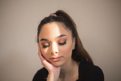 Close-up of young woman against gray background