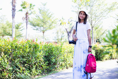 Portrait of a smiling young woman standing against plants