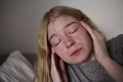 Young woman touching temples with closed eyes