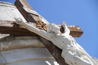 Low angle view of crucifix against clear blue sky