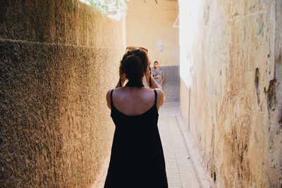 Rear view of woman standing against wall