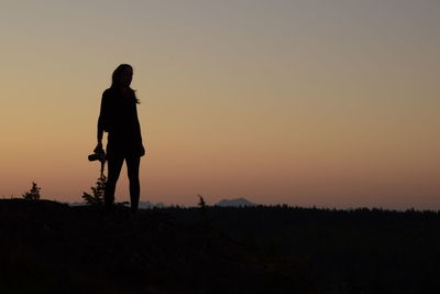 Silhouette person standing on shore against sky during sunset