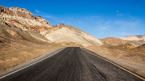 Road leading towards mountains against sky