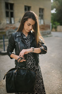 Attractive young woman with leather jacket standing outdoors.