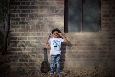 Portrait of boy standing against brick wall