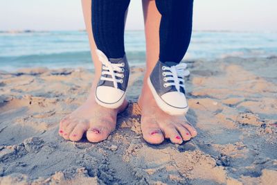 Low section of mother with son standing on beach