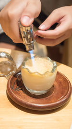 Close-up of hand holding drink served on table