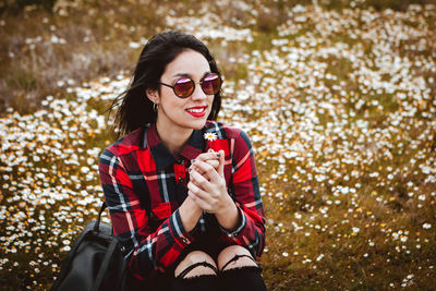 Smiling young woman wearing sunglasses sitting on land