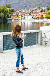 Woman using mobile phone while standing on bridge