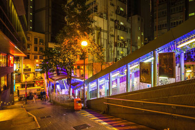 Illuminated street amidst buildings at night