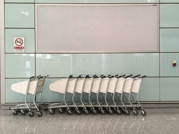 Shopping cart arranged on tiled floor by wall in mall