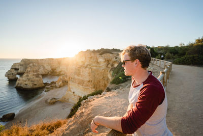 Man standing by railing against clear sky