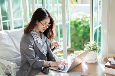 Young woman using phone while sitting on table