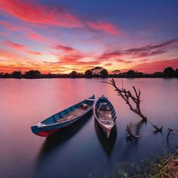 Boat moored in lake during sunset