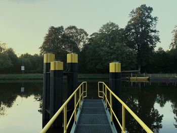 Footbridge over lake against sky