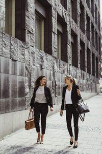Businesswomen talking while walking by building