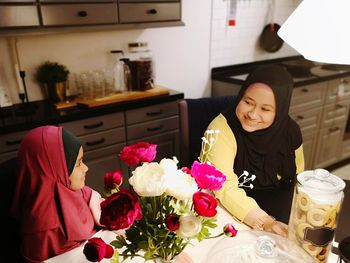 Woman sitting on table by potted plant