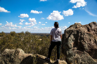 Woman standing on mountain against cloudy sky