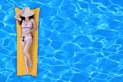 High angle view of woman on inflatable raft in swimming pool