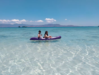 People on boat in sea against sky