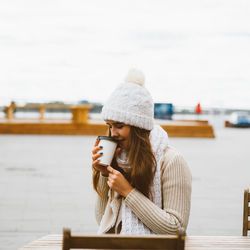 Young woman drinking coffee while sitting at outdoor cafe