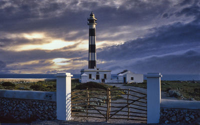 Lighthouse by building against sky