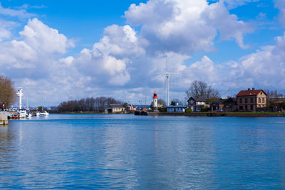 Boats in harbor against cloudy sky