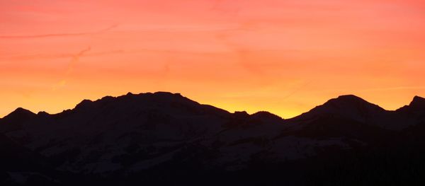 Scenic view of silhouette mountains against orange sky