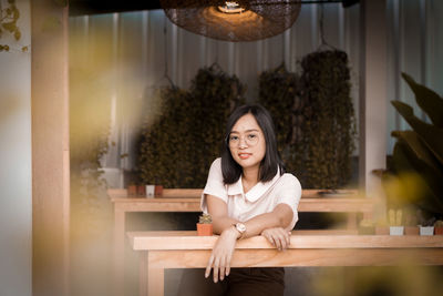 Portrait of young woman sitting on table