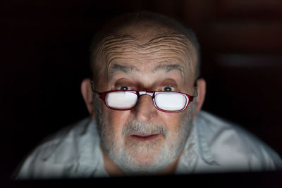 Senior man wearing eyeglasses with reflection of computer