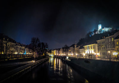 Boats moored on illuminated city against sky at night