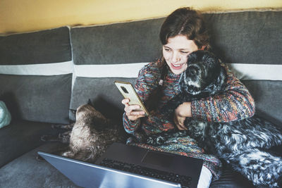 Happy woman with pets using smart phone at home