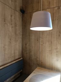 Illuminated lamp over table against wall at home