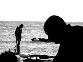 Rear view of silhouette people on beach against clear sky