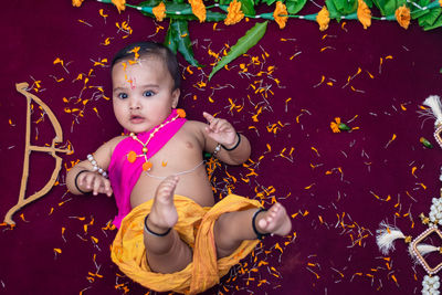 Cute indian boy dresses as lord rama with bow and flowers from top angle