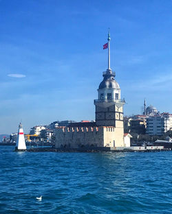 View of lighthouse by sea against buildings