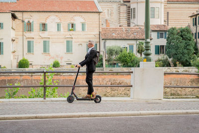 Man riding motorcycle on road against buildings