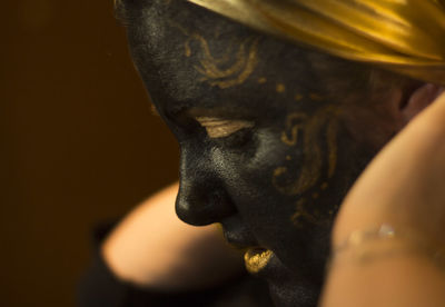 Portrait of a woman with black and gold make up, close up